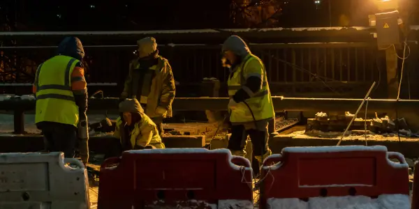 construction workers at night digging underground groundworks.