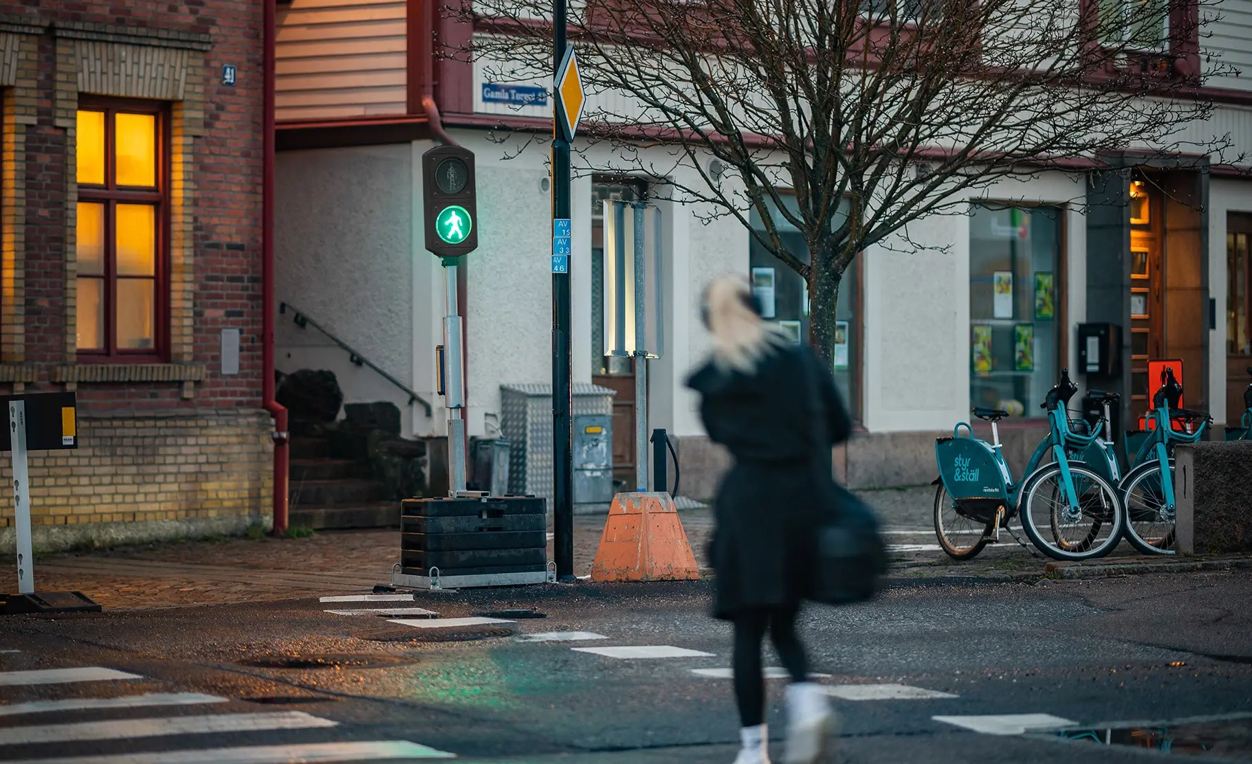 Pedestrian crossing the road using Berlex pedestrian signals showing green light.